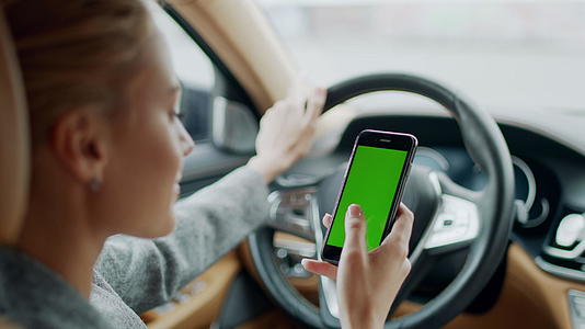 女性在车内使用绿屏手机视频的预览图