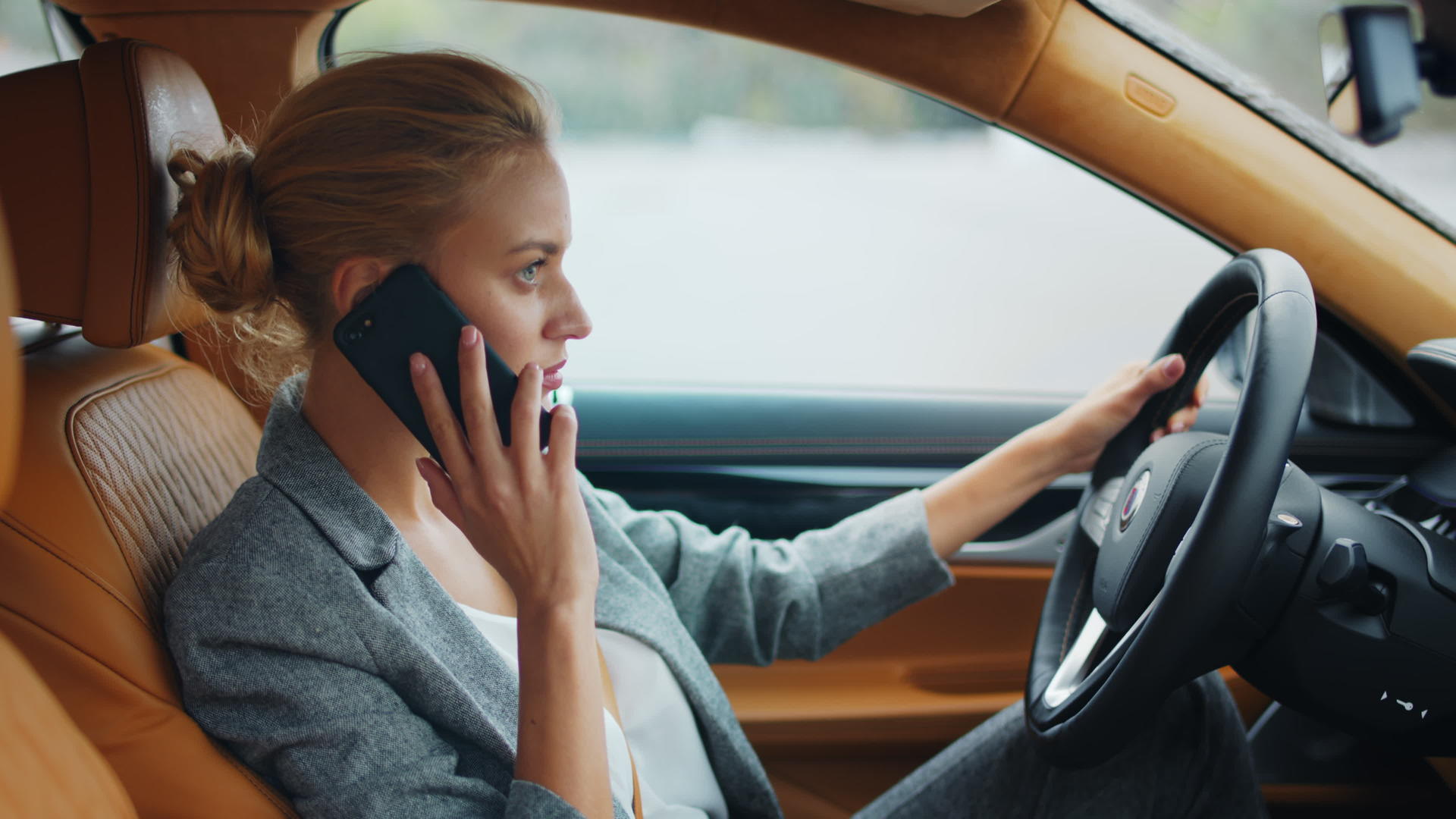 白领女性坐在豪华轿车驾驶座上打电话视频的预览图