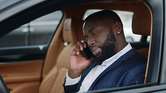 商务白领男性在汽车上使用手机进行交谈和交流视频的预览图