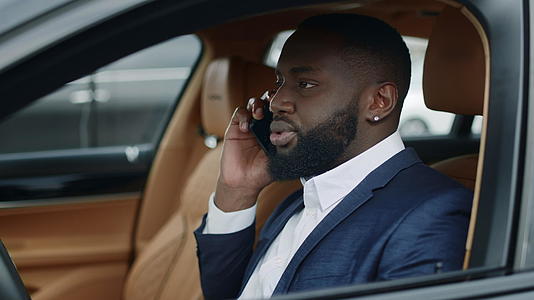 商务白领男性在汽车上使用手机交谈和争论视频的预览图