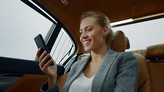 白领女性微笑着用手机看车里的消息视频的预览图