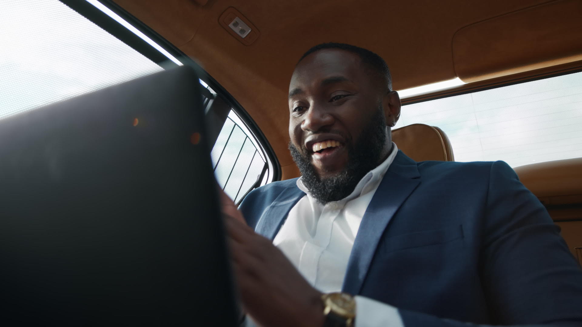 坐在汽车后座的白领男人用笔记本电脑工作快乐地拍手视频的预览图