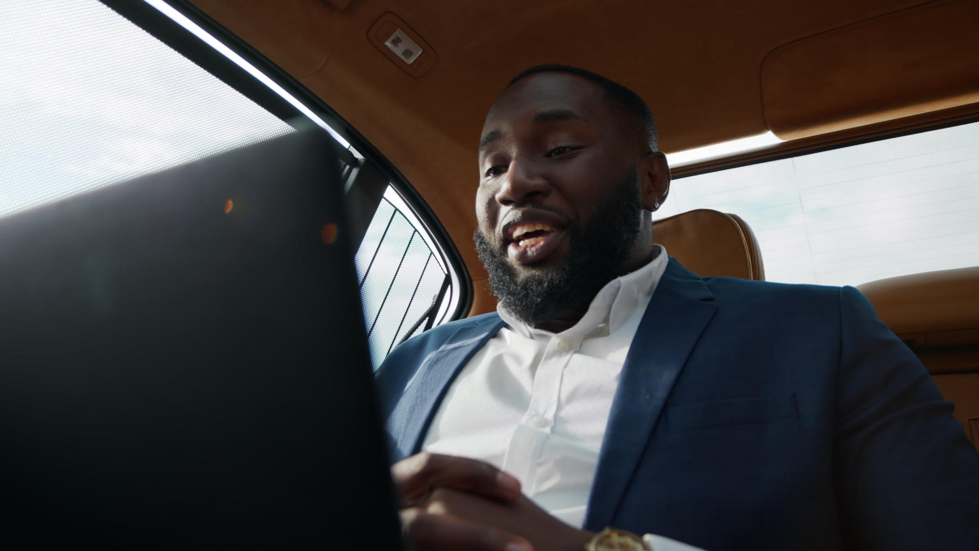 坐在车后座的白领男用笔记本电脑愉快地工作和交流视频的预览图