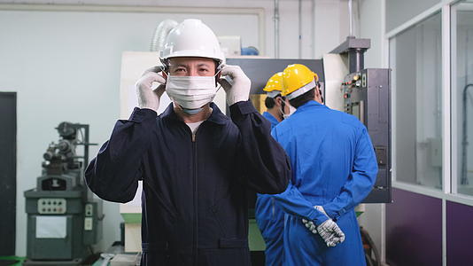 工厂工人戴着口罩在后面用机器工作视频的预览图