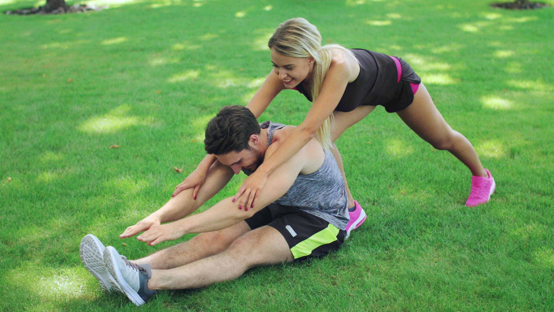 女运动教练帮助健身男子在夏季公园伸腿视频的预览图