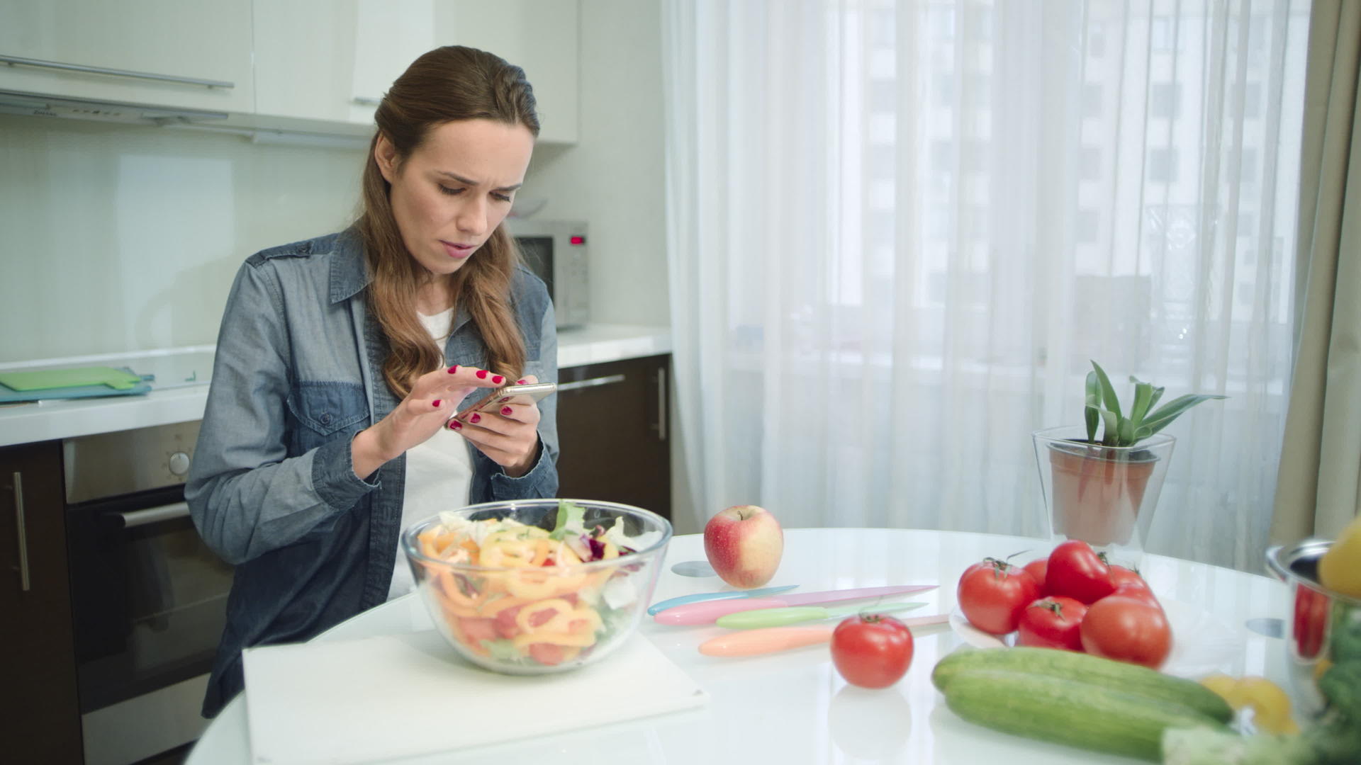 现代厨房中使用移动电话的女性视频的预览图