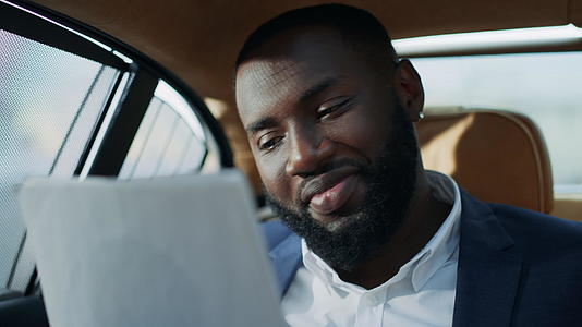 非洲商人在汽车上看文件时微笑视频的预览图