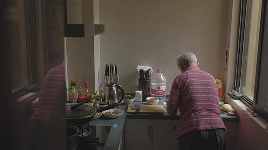 老人厨房忙碌背影视频的预览图