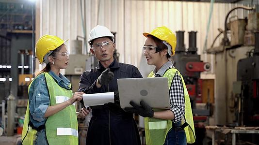 一群工厂男女工人用平板电脑和纸质文件报告会议和讨论视频的预览图