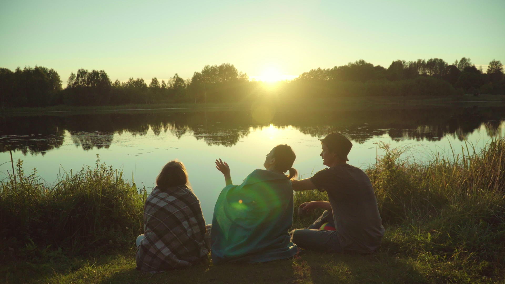 年轻人享受在河岸度假和日落视频的预览图