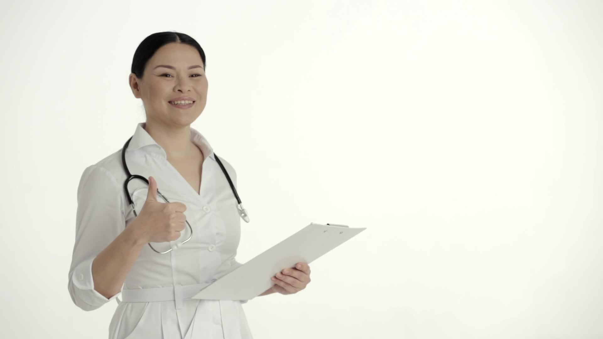 亚洲护士在白色背景下微笑举起拇指视频的预览图