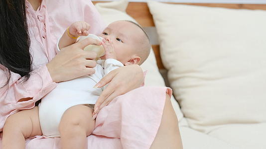新生婴儿躺在他年轻母亲的膝盖上喝瓶装牛奶视频的预览图