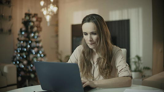 在圣诞之家从事笔记本电脑工作的年轻女性视频的预览图
