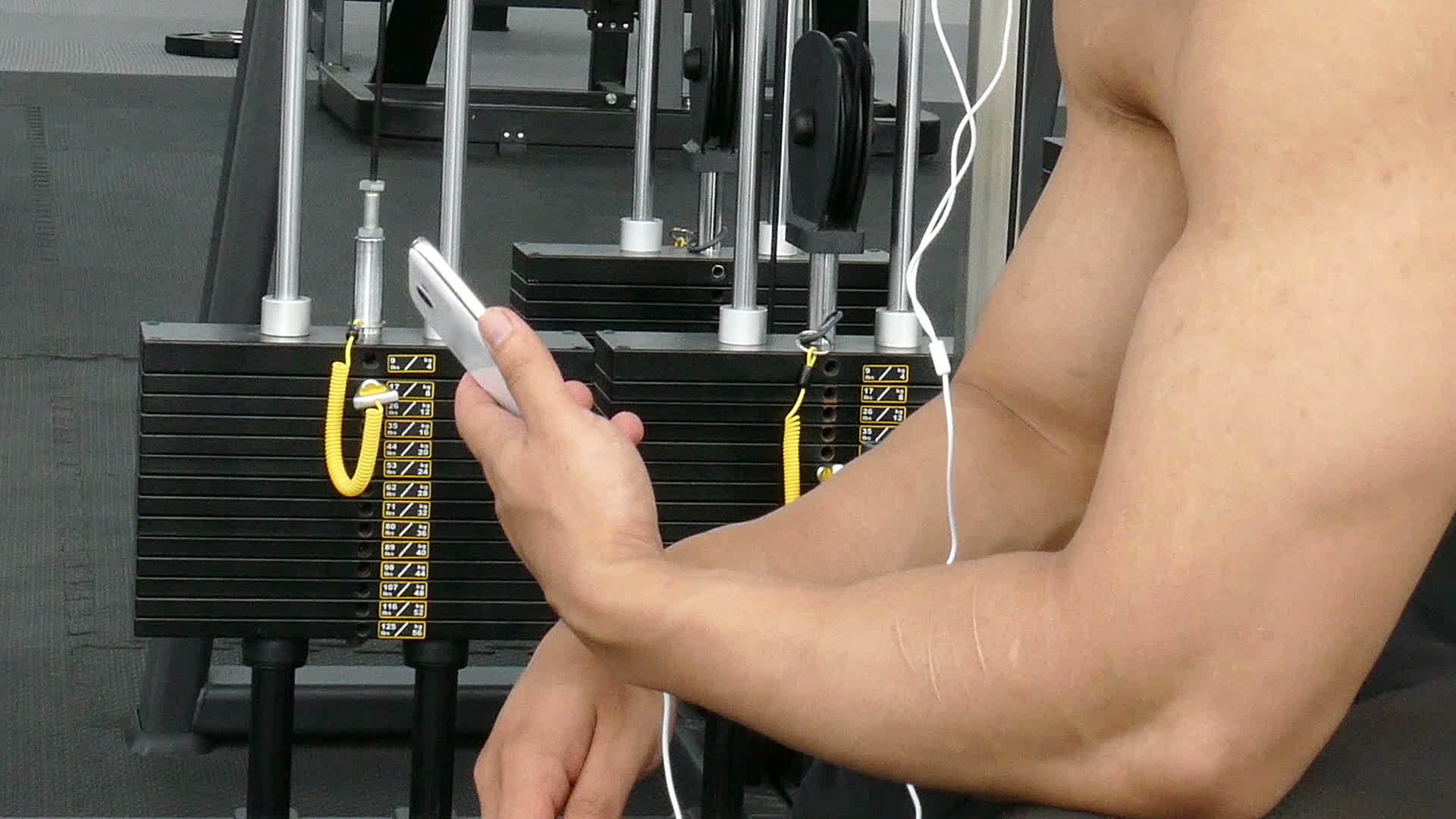 男运动员在健身房用手机听音乐视频的预览图