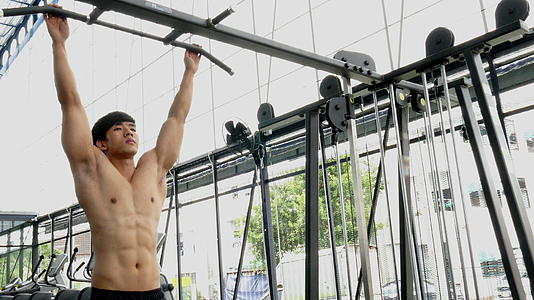 年轻的肌肉男在健身中心用机器锻炼视频的预览图