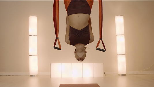 女人倒挂在工作室的瑜伽带上视频的预览图