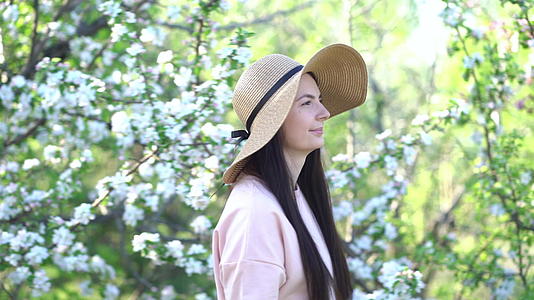 美丽的年轻女性享受盛开的苹果花春果园视频的预览图