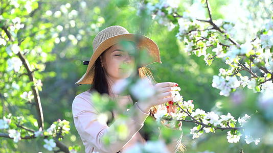 美丽的年轻女性享受盛开的苹果花春果园视频的预览图