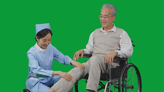 4K绿幕女护士给老年病人按摩腿部视频的预览图