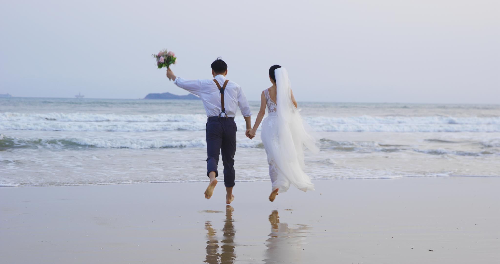 8K沙滩上牵手跑向海水的婚纱情侣背影视频的预览图