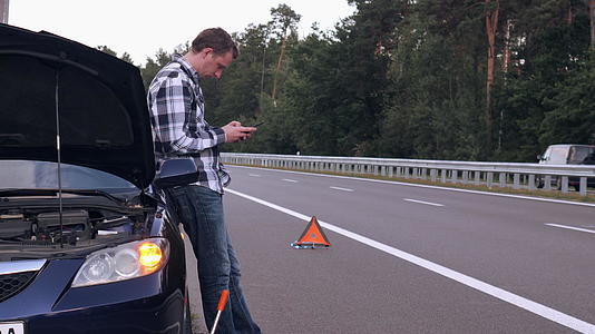 男子的车辆损坏站在车辆旁边用手机求助视频的预览图