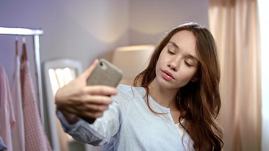 年轻女性在家用手机自拍视频的预览图
