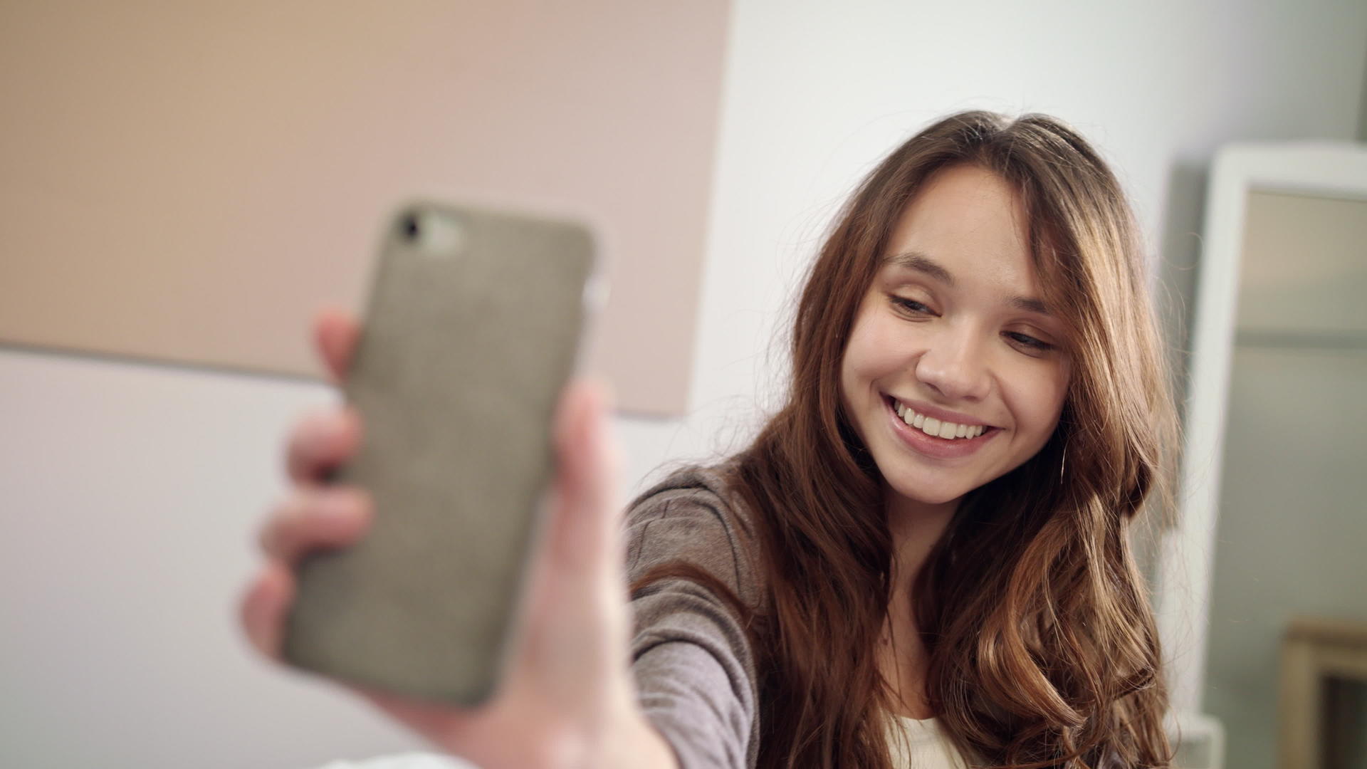年轻女性在卧室的手机上自拍视频的预览图