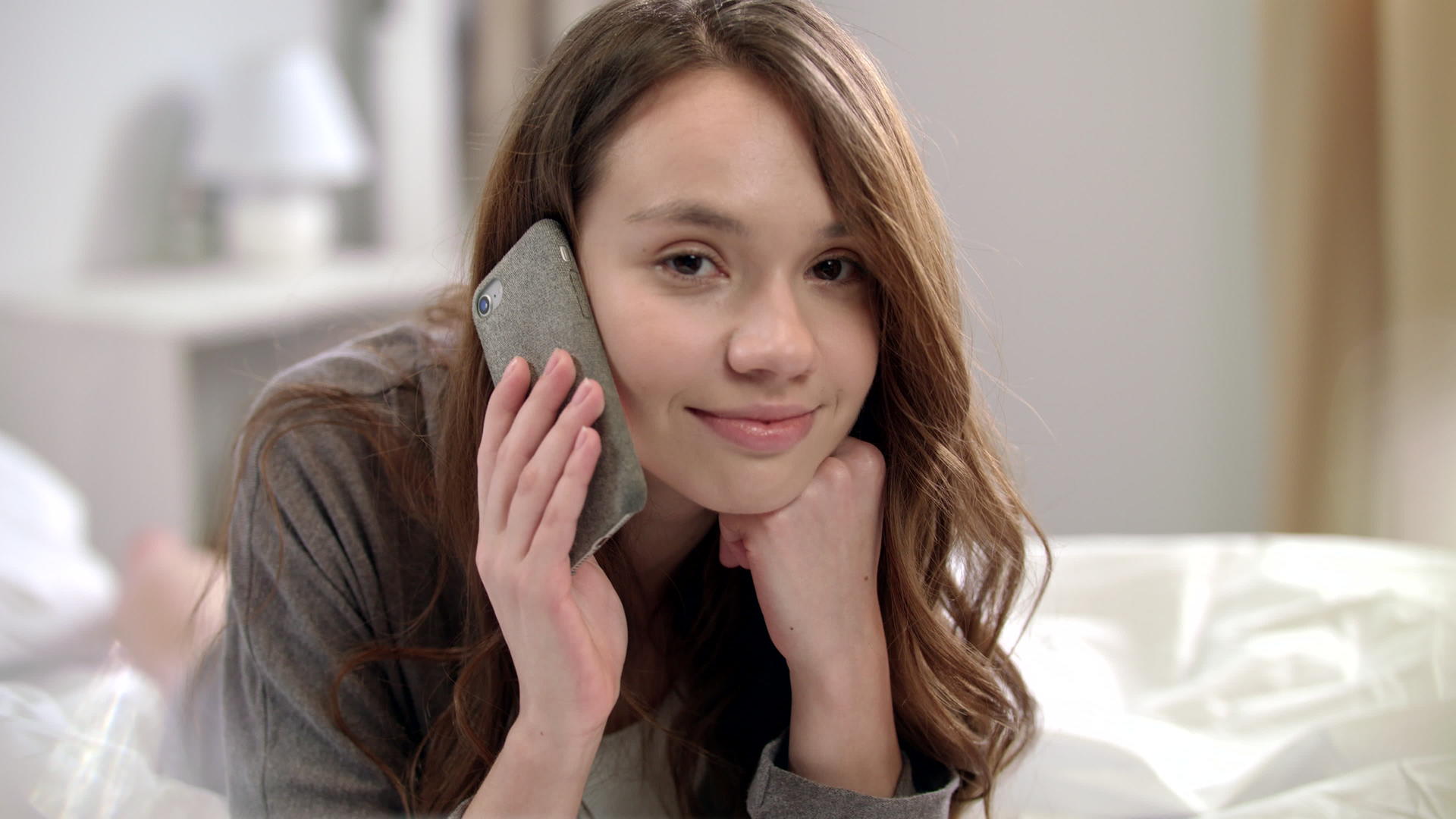 在床上用手机说话的年轻女性视频的预览图