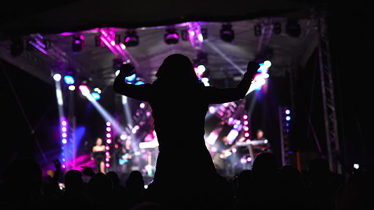 女孩坐在音乐会的肩膀上举起手视频的预览图