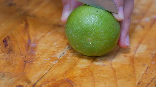 将绿色柑橘切成两半切在厨房的切割板上视频的预览图