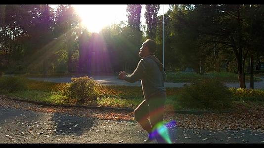 男人在阳光下在绿色的秋林中奔跑视频的预览图