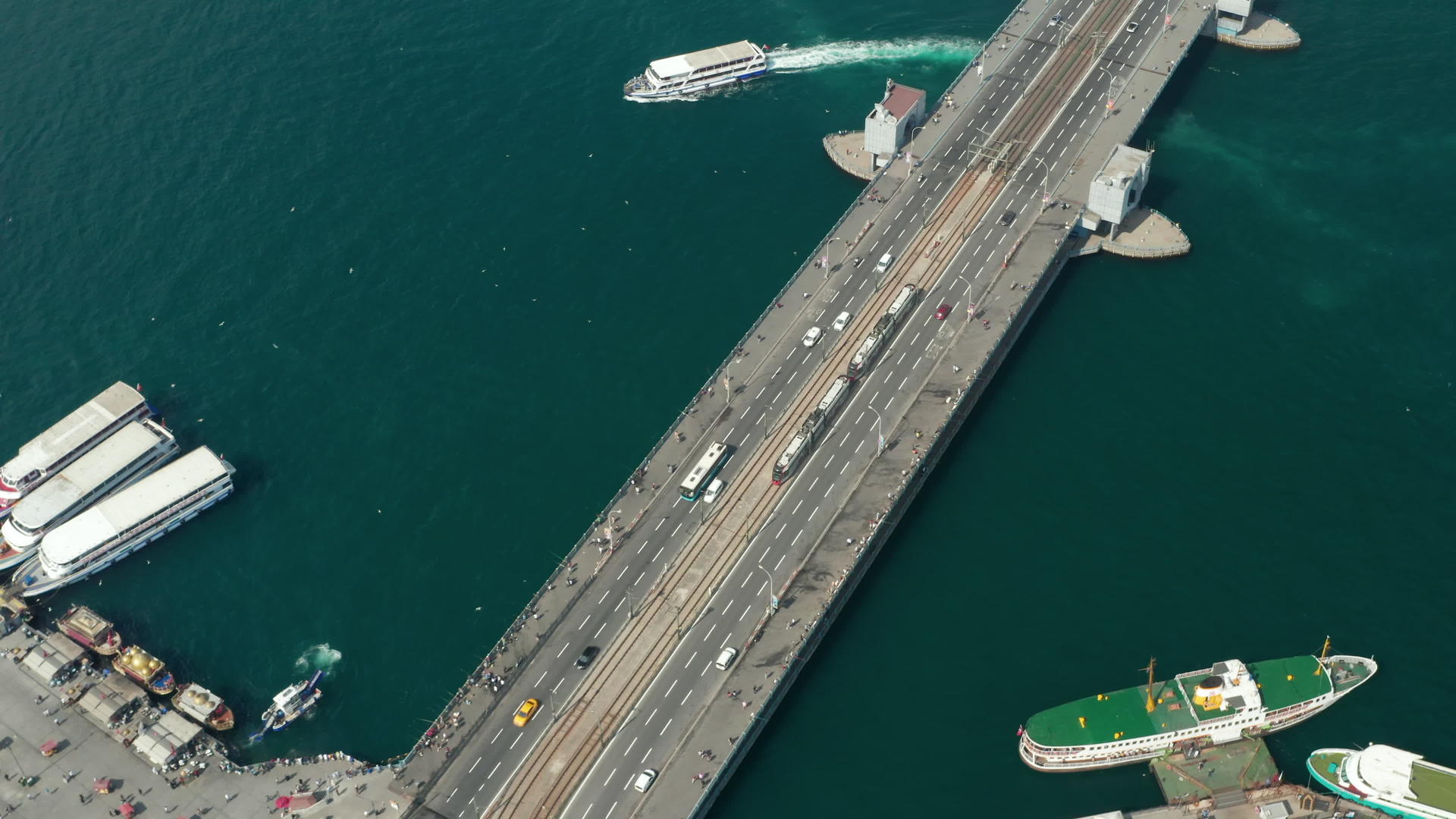 有轨电车列车经过伊斯坦布尔博斯普鲁斯海峡的加拉塔大桥海鸥和船只在水上在空中的低角拍摄4K视频的预览图