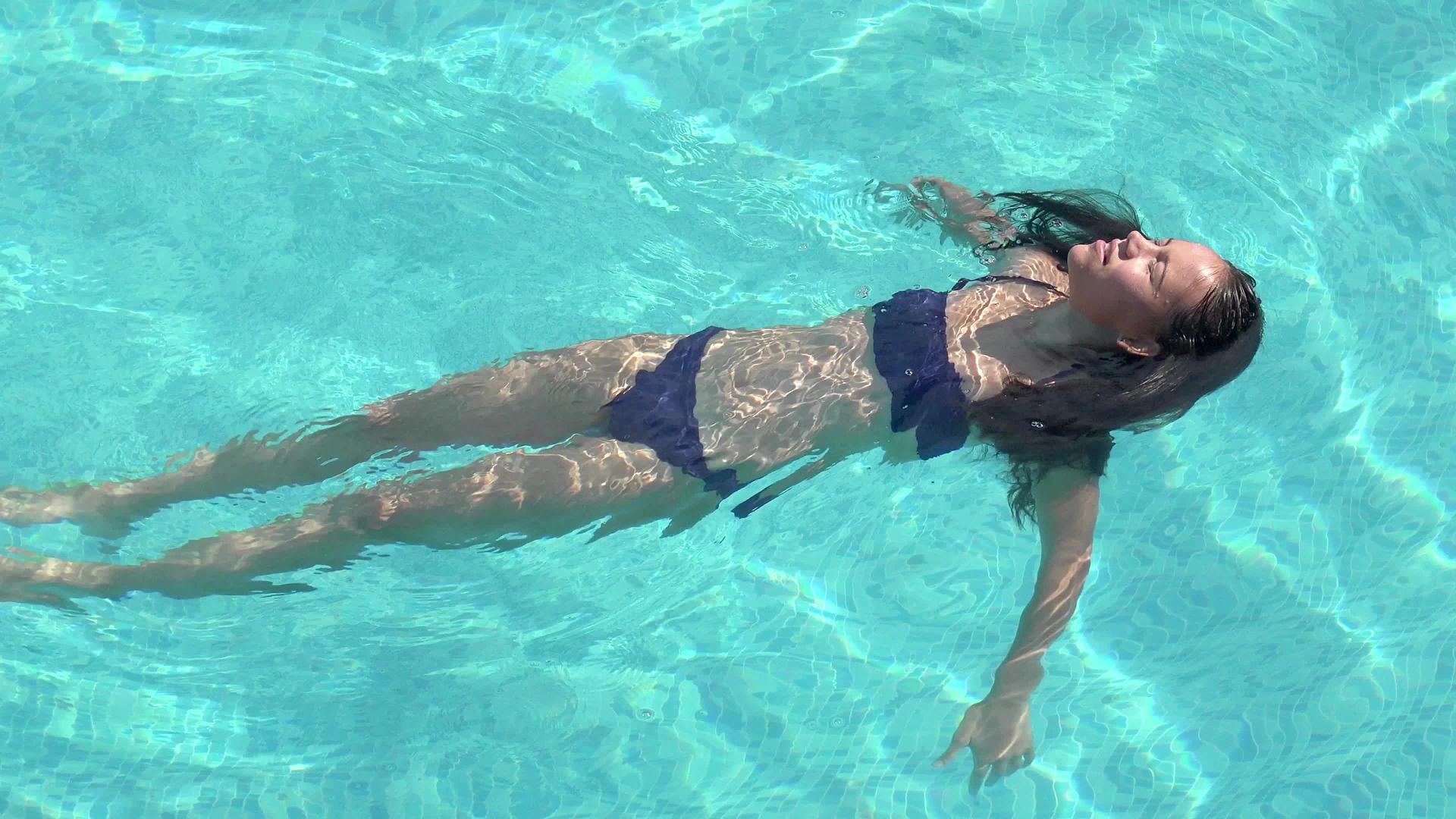 女人穿比基尼躺在海滩游泳池的水上空中射击视频的预览图