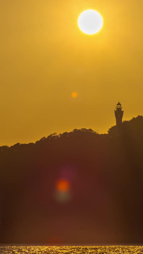 太阳从岛灯塔上落下夕阳西下视频延时视频的预览图