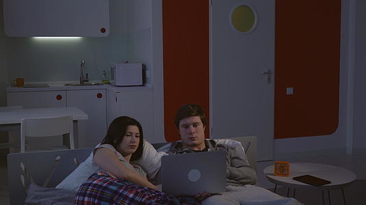 女人和男人躺在床上看视频视频的预览图