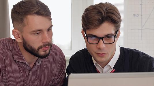 男人在眼镜里向男同事解释笔记本电脑上的事情视频的预览图