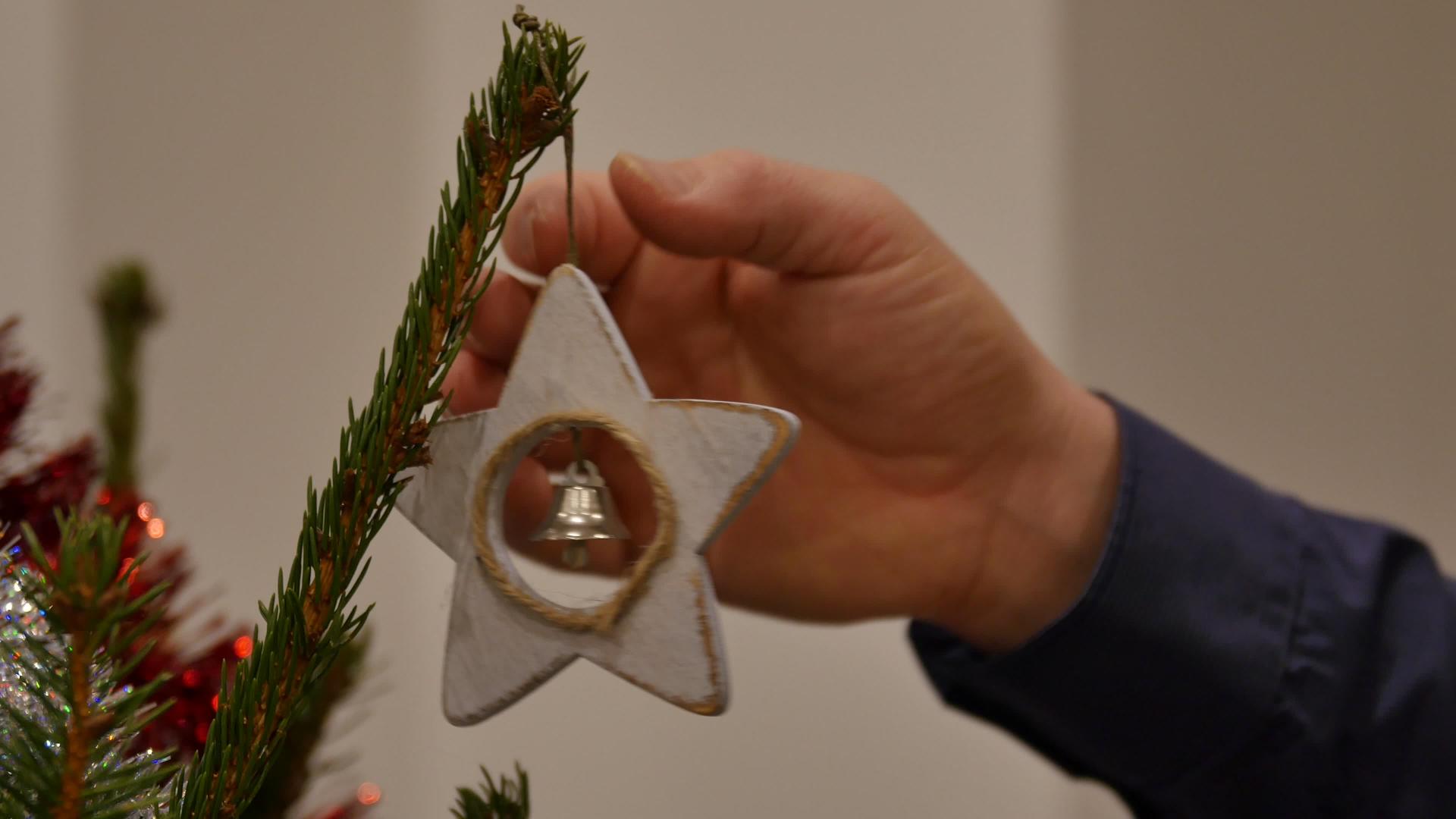 男人把心形的铃铛挂在天然松树圣诞树上视频的预览图