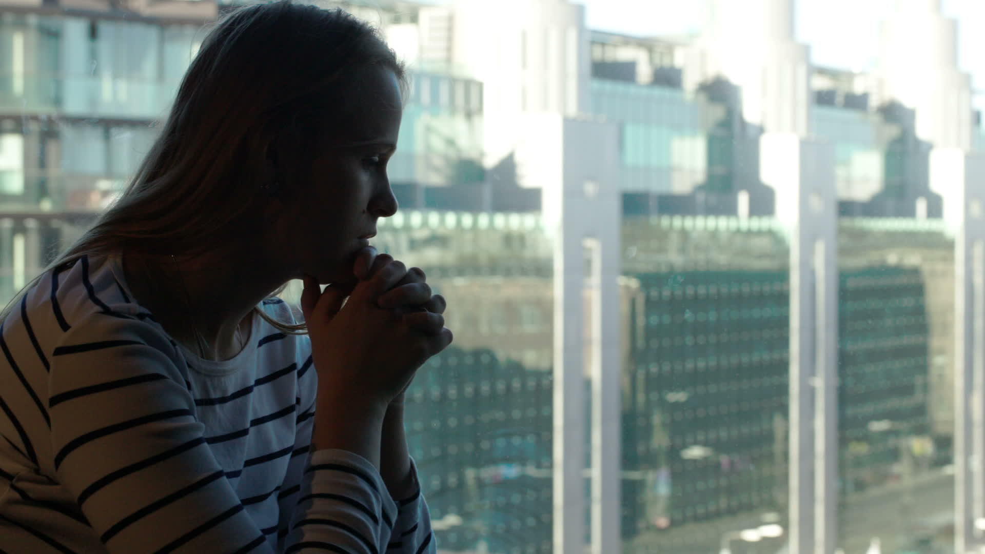 悲伤的女人有着深沉的思绪然后用城市的风景看着窗外的窗户视频的预览图
