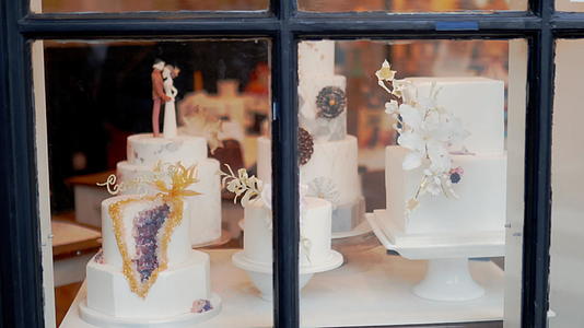 在面包店的窗户上穿过一个小而华丽的婚礼蛋糕视频的预览图