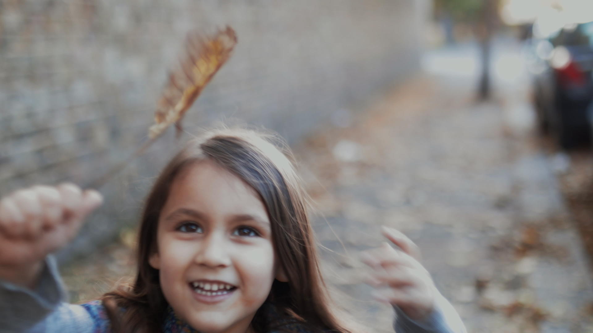 小女孩跑在人行道上向镜头展示秋叶视频的预览图