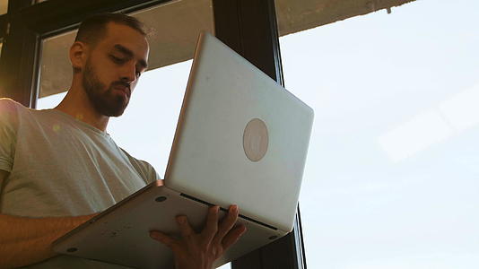 笔记本电脑操作经理在窗口附近的低角度拍摄视频的预览图