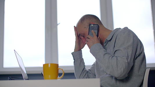压力男人在工作场所用智能手机说话的观点视频的预览图