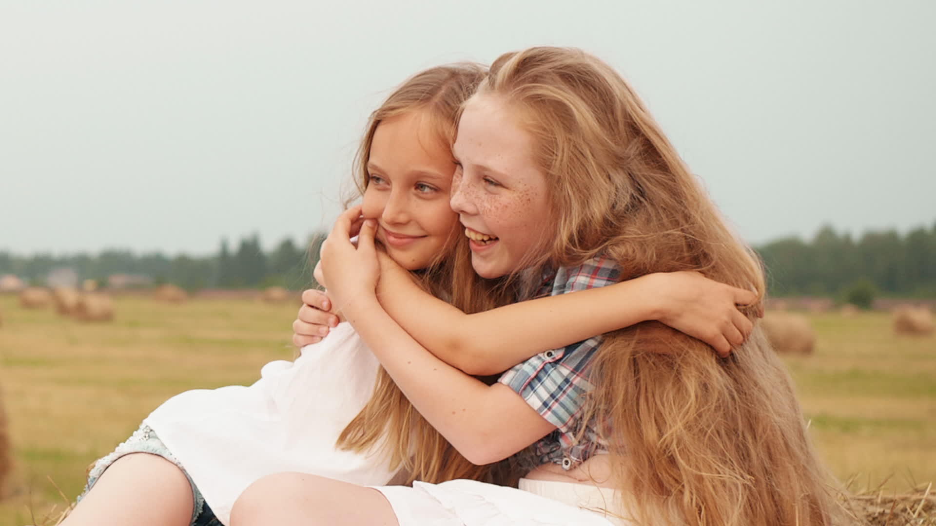 草堆上的两个女孩拥抱在一起视频的预览图