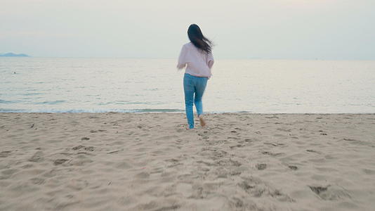 快乐的女人在热带海滩享受暑假赤脚奔向大海张开双臂视频的预览图