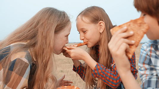 顽皮的女孩在农村田野里吃了两个披萨视频的预览图