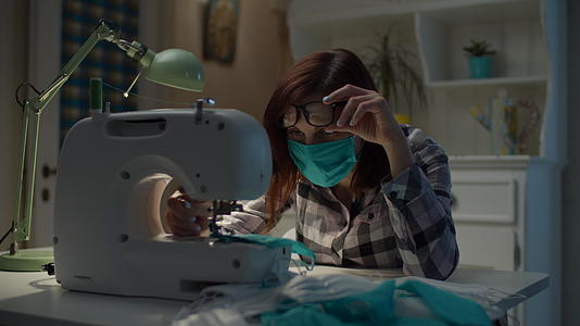 戴口罩的女性在缝纫机上缝制防护口罩视频的预览图