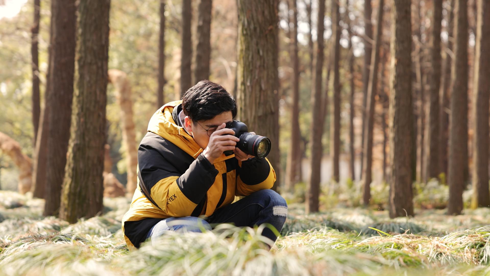 树林里蹲下拍照片的摄影师视频的预览图