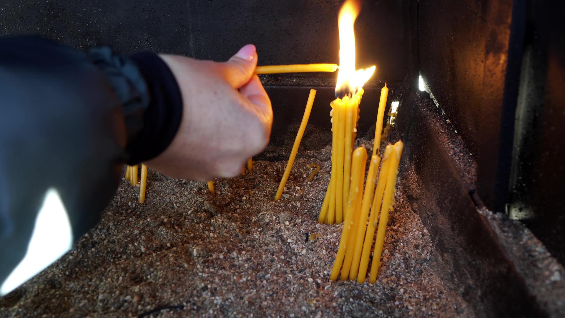 教堂里的妇女用手点燃蜡烛视频的预览图