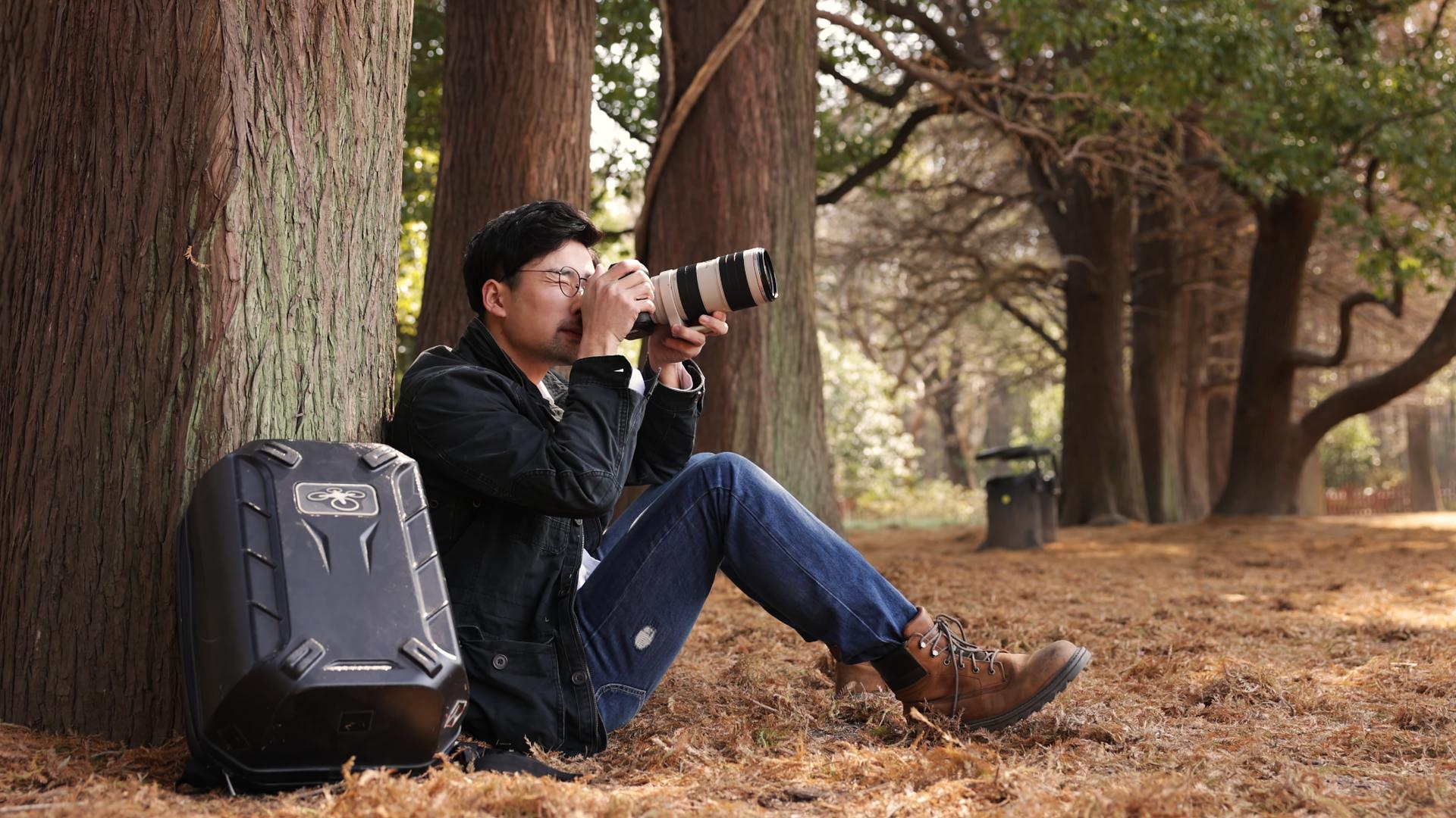 坐在树下拍照的摄影师视频的预览图