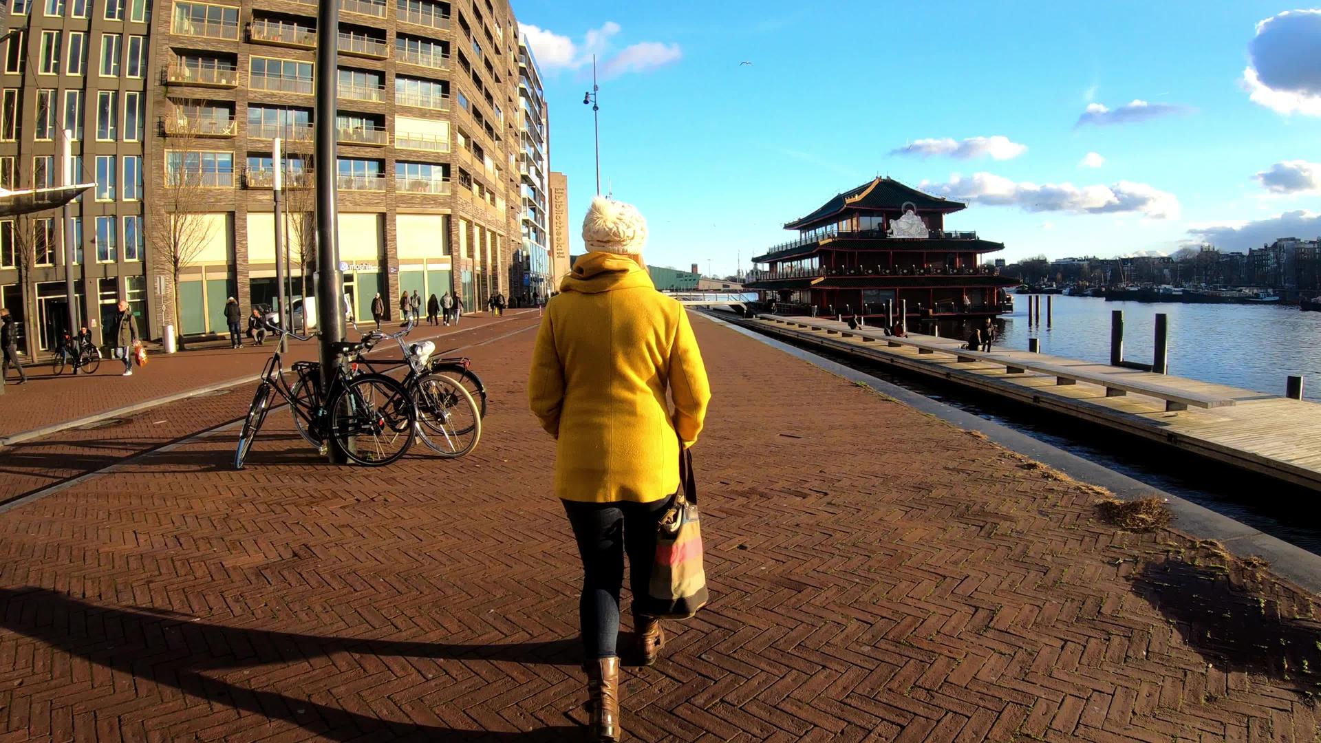 妇女穿过阿姆斯特丹运河游客探索阳光明媚的阿姆斯特丹日视频的预览图